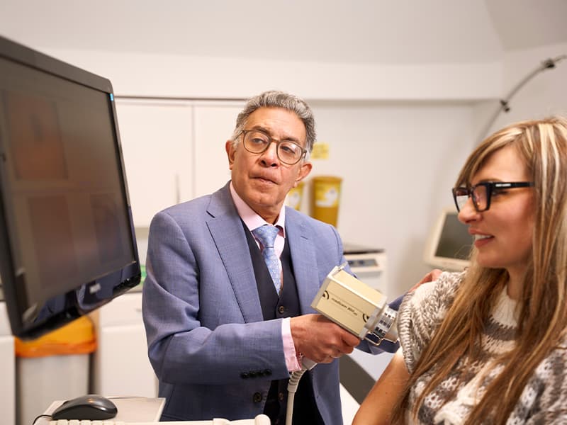 Dr Sunil Chopra examining a patient with a skin-analysis device